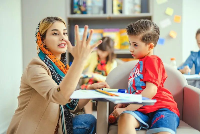 A teacher working with a boy in a classroom